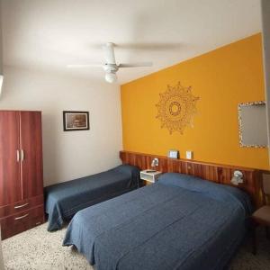 um quarto com 2 camas e uma parede amarela em Hostería Altea em Monte Hermoso