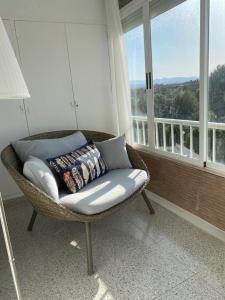 een rieten stoel in een kamer met een groot raam bij Apartamento RosarioyEmma - Primera línea de playa con vista mar in Jávea