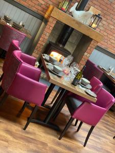 a table with purple chairs in front of a fireplace at Atholl Arms Hotel Dunkeld in Dunkeld