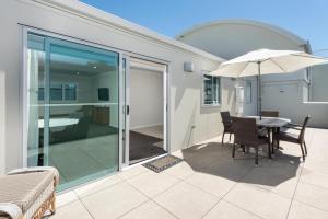 a patio with a table and chairs and an umbrella at Modern Marine Parade Apartment in Mount Maunganui