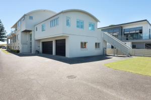 una gran casa blanca con garaje en Modern Marine Parade Apartment, en Mount Maunganui 3 fotos más