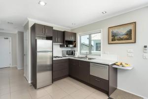 a kitchen with a stainless steel refrigerator and a window at Modern Marine Parade Apartment in Mount Maunganui