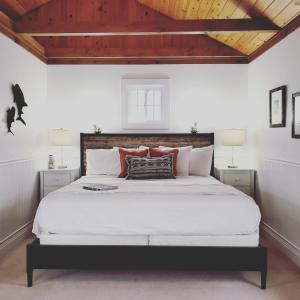 a bedroom with a large white bed with a wooden ceiling at Sand Bar Cottage Inn in Bar Harbor