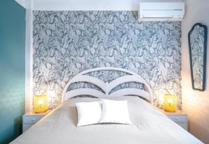 a bedroom with a white bed with a blue and white wallpaper at Appartement Barcares Village VUE MER in Le Barcarès