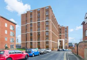 Un edificio de ladrillo con coches aparcados delante. en LillyRose Serviced Apartments - St Albans City Centre, Parking, en Saint Albans