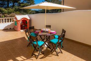 una mesa y sillas con una sombrilla en el patio en Villa Mariposa con Piscina Privada, en Son Serra de Marina