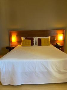 1 cama blanca grande con 2 almohadas amarillas. en Apart-hotel, piscina, TV a cabo, academia, en Joinville
