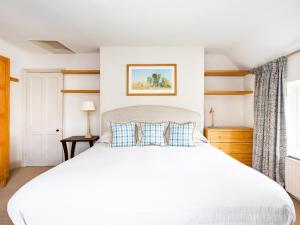 Un dormitorio con una gran cama blanca y una ventana. en Gardeners Cottage, en Chipping Norton