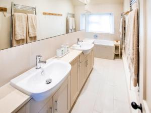Un baño blanco con dos lavabos y un espejo. en Gardeners Cottage, en Chipping Norton 21 fotos más