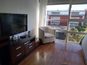 a living room with a television and a white chair at Edificio San Diego in Mar del Plata