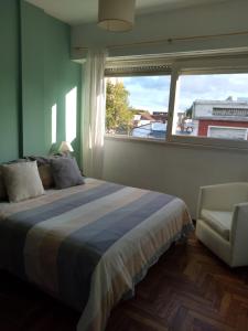 1 dormitorio con cama, ventana y silla en Edificio San Diego en Mar del Plata