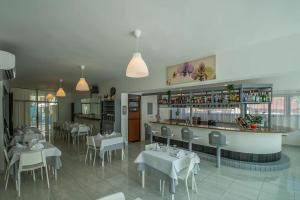 a restaurant with white tables and chairs and a bar at Europa Hotel and Condo in Sosúa