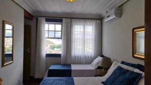Hotel Pousada Casa Grande في أورو بريتو: غرفة نوم بسريرين ونافذة