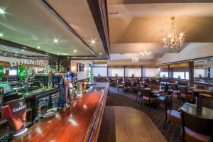 a restaurant with a bar and tables and chairs at The Burnside Hotel in Glasgow