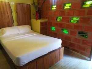 - un lit avec des lumières vertes sur un mur en briques dans l'établissement Hotel B & C, à Mariquita