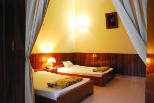 a bedroom with two beds and a window with two lamps at Hai Huong Hotel in Quy Nhon
