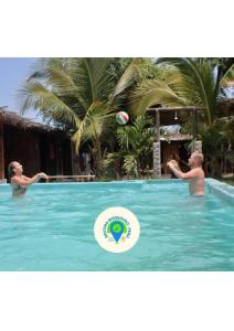 2 personnes jouant avec un volley-ball dans la piscine dans l'établissement Saigon Backpackers hostel, à Máncora