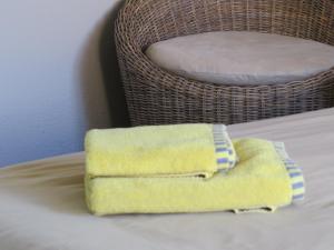 a yellow towel sitting on top of a bed with a basket at Beach Walk House and Cottage - Self Catering in Swakopmund