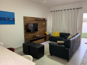a living room with a couch and a flat screen tv at Casa Búzios - Temporada in Búzios