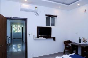 a living room with a television and a room with a table at Casillda Munnar in Munnar