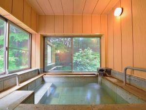 uma banheira de hidromassagem num quarto com duas janelas em Jizaiso em Nasu