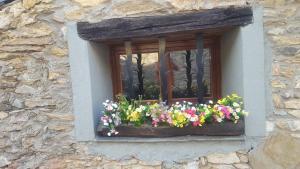 una ventana con un ramo de flores en una caja de la ventana en CAL GERARD - ARCAVELL, en Arcabell