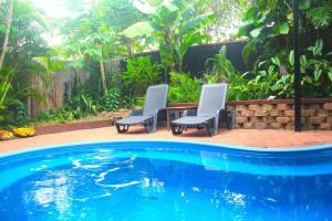 two chairs and a table next to a swimming pool at Elevated Tropical House in Casuarina