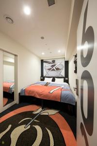 1 dormitorio con 1 cama con colcha de color naranja en HOTEL TAVINOS Hamamatsucho, en Tokio