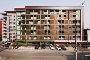 a large apartment building with cars parked in a parking lot at Cross Vibe Chiang Mai Decem, Nimman in Chiang Mai