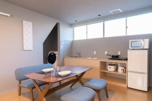 a kitchen with a table and two chairs and a kitchen with a refrigerator at Koshomachi Stay in Kanazawa