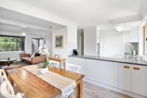 a kitchen and living room with a wooden table and a dining room at Lennox Belle in Lennox Head