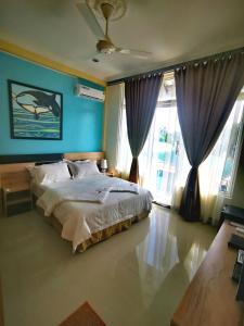 a bedroom with a bed with blue walls and windows at Mirian Sky in Gaafaru