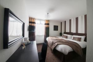 um quarto com uma cama grande e uma televisão em The Burnside Hotel em Glasgow
