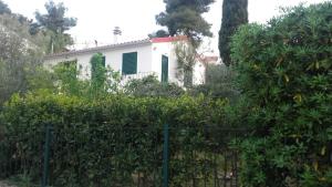a white house with green shutters behind a fence at Holiday home Pavarotti in Supetar