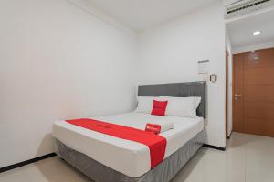 a bedroom with a bed with a red blanket on it at RedDoorz Syariah near Regol Park Bandung in Bandung