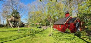 een rode schuur met een zwart dak in een veld bij Het Kleine Paradijs in Easterein