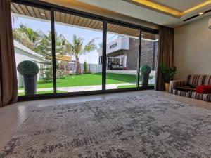 an open living room with a large window and a large rug at G R A N D C H A L E T in Salalah