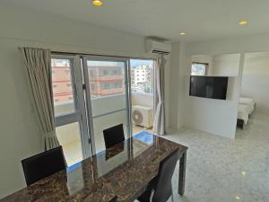een woonkamer met een glazen tafel en een televisie bij G-RATIS Omoromachi in Naha