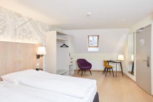 
a room with a bed, chair, table and a lamp at Kreuz Bern Modern City Hotel in Bern
