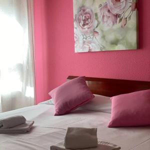 una camera da letto con pareti rosa e un letto con cuscini rosa di Hostal San Andrés a Soria