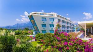 a white building with flowers in front of it at Daima Biz Hotel - Dolusu Aquapark Access in Kemer