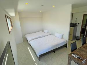 a small room with two beds and a table at G-RATIS Omoromachi in Naha