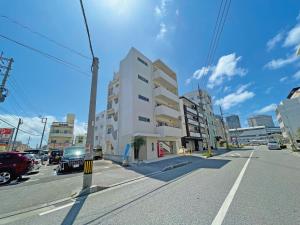 une rue avec un bâtiment blanc sur le côté de la route dans l'établissement G-RATIS Omoromachi, à Naha