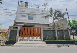 a white house with a gate and a palm tree at RedDoorz Syariah @ Boemi Guesthouse Tasikmalaya in Tasikmalaya