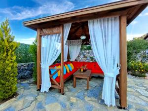 a gazebo with a red couch on a patio at Villa Kayakoy 3 in Fethiye