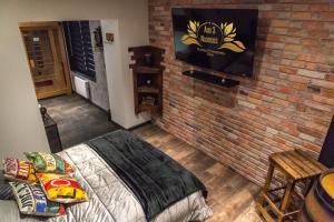 una camera da letto con un muro di mattoni, un letto e una TV di Aux 3 Nuances Suites Privatives & Spa a Calais