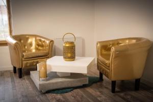 dwa złote krzesła i stół z lampą w obiekcie Aux 3 Nuances Suites Privatives & Spa w Calais