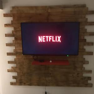 una tv su un muro con un cartello netflix di Aux 3 Nuances Suites Privatives & Spa a Calais