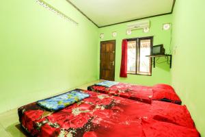 Schlafzimmer mit einem Bett mit roter Bettwäsche und einem Fenster in der Unterkunft Penginapan Roro Mendut Syariah in Magelang