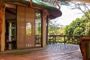 eine Veranda eines Hauses mit einer Holzterrasse in der Unterkunft PrideInn Mara Camp & Cottages in Talek